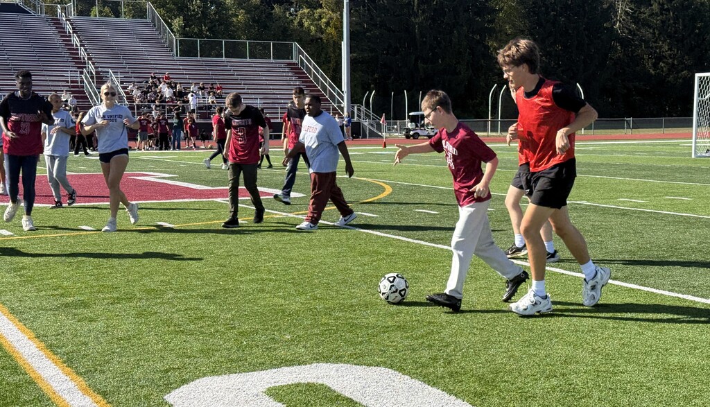 Several soccer players maneuvering for a ball on a field