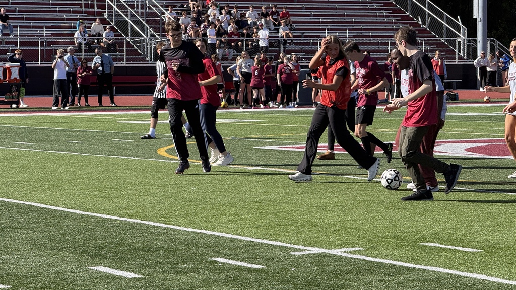 Several soccer players maneuvering for a ball on a field
