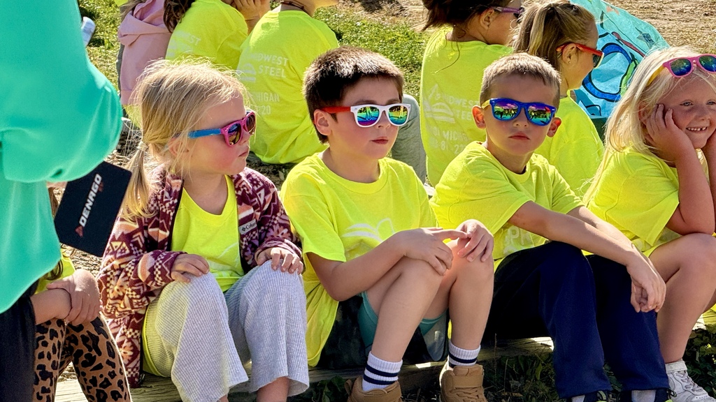 Young students sitting outside in yellow shirts with sunglasses on 