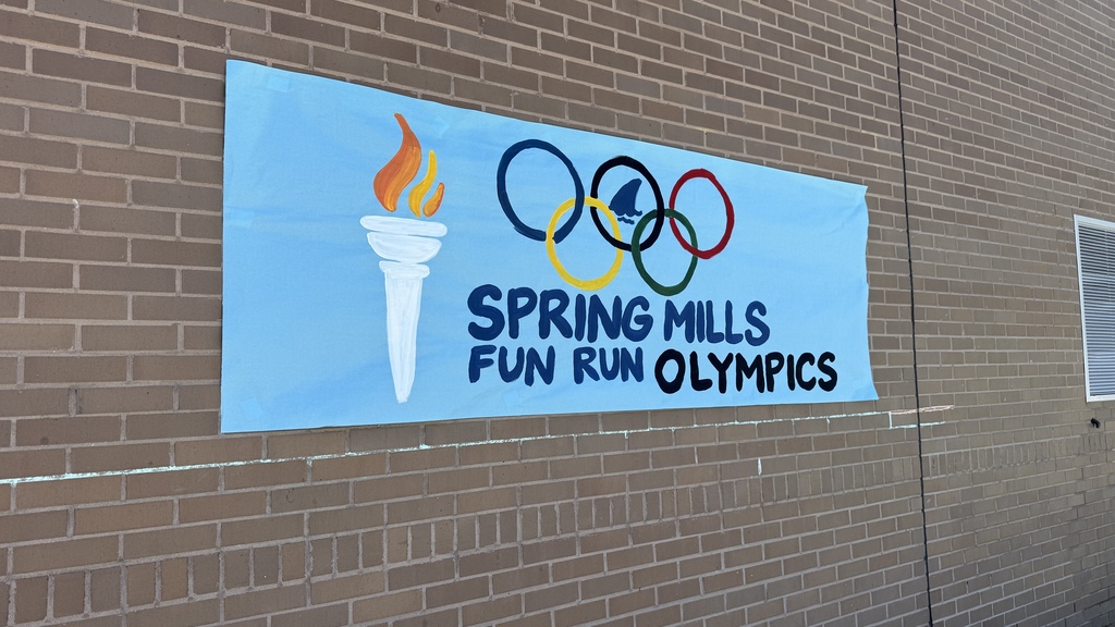 A blue poster on a brick wall that reads" spring mills fun run olympics"