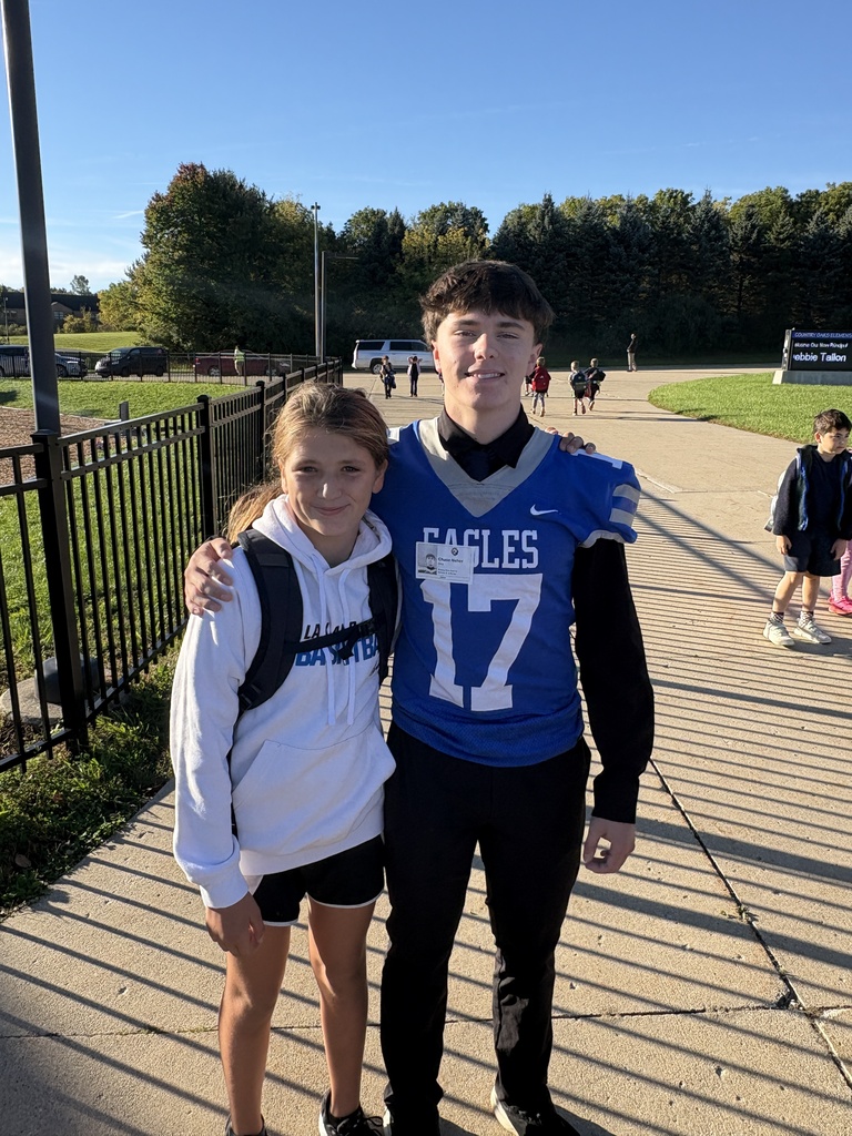 Football player in jersey posing & smiling with younger students for a photo