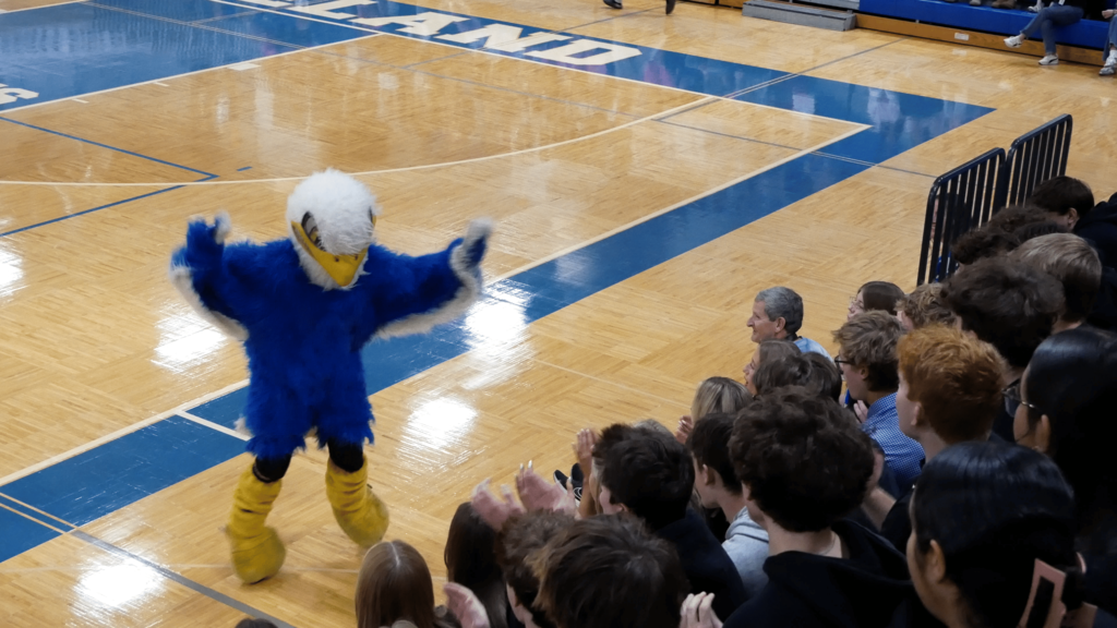 An eagle mascot hyping up the crowd during a gym rally