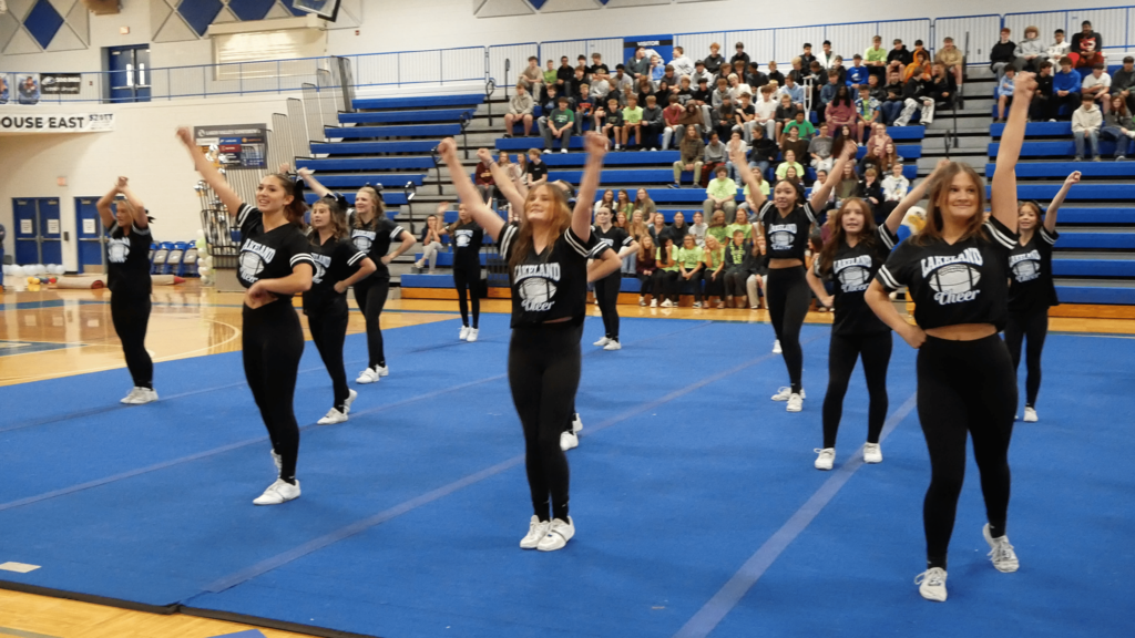 Female students doing cheer routine on gym floor