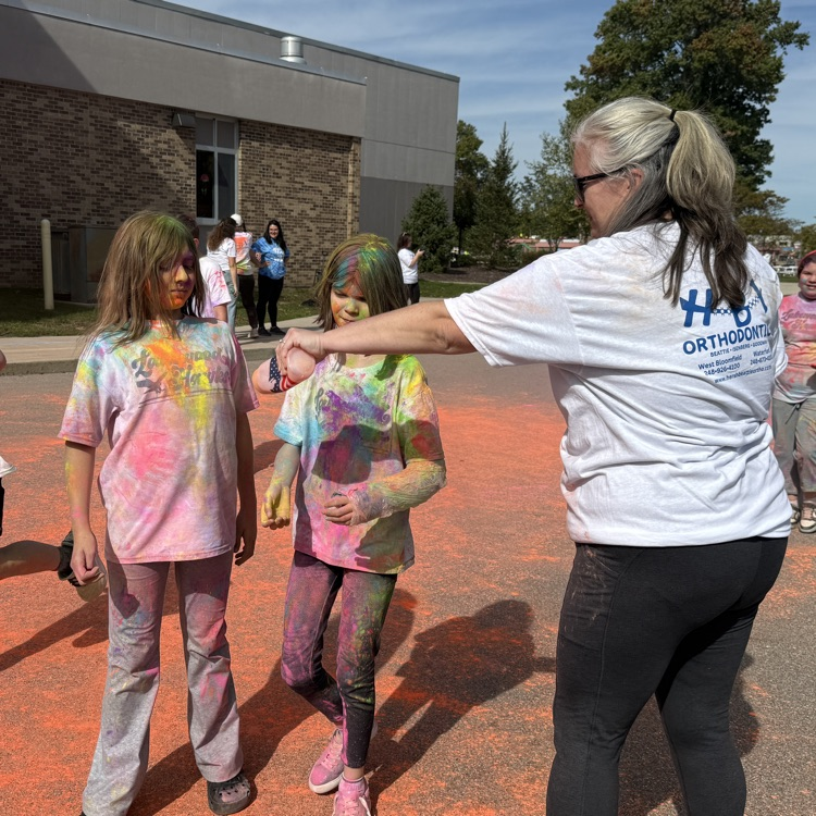 school kids covered in colored powder walking outside