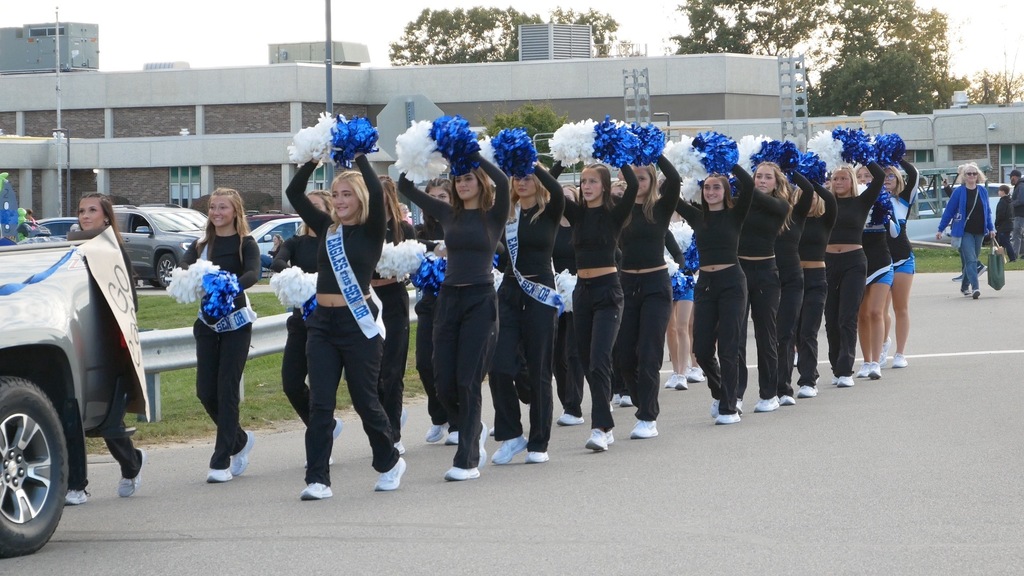 Teen girls holding pop pons walking in a parade