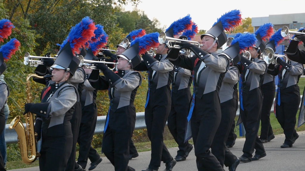 Teen band members marching in parade holding trumpets