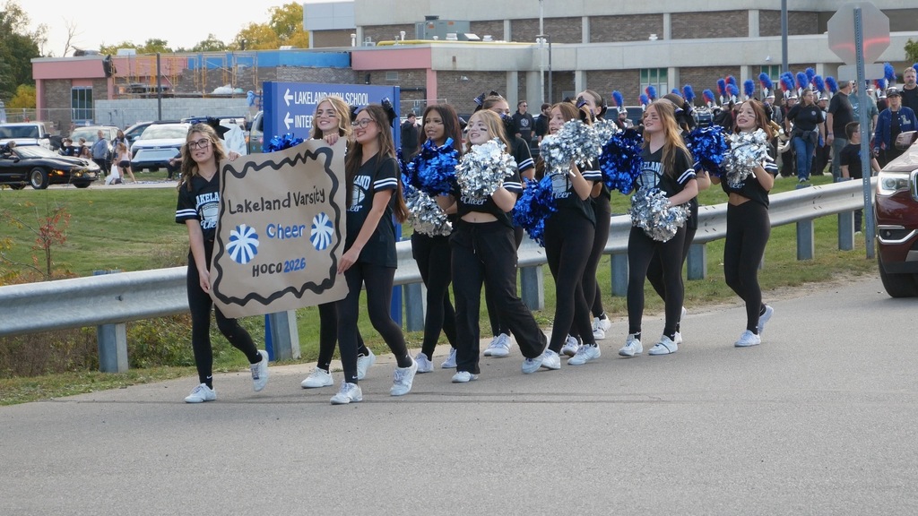 Teen girls holding pom pons walking in a parade