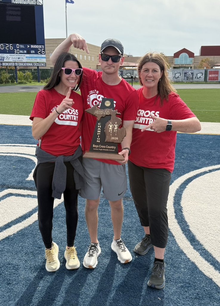 three coaches holding a trophy with thumbs up wearing red shirts