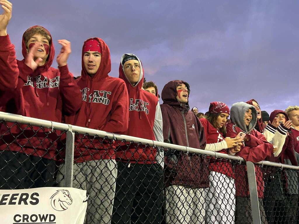 Teen fans in the bleachers standing wearing red