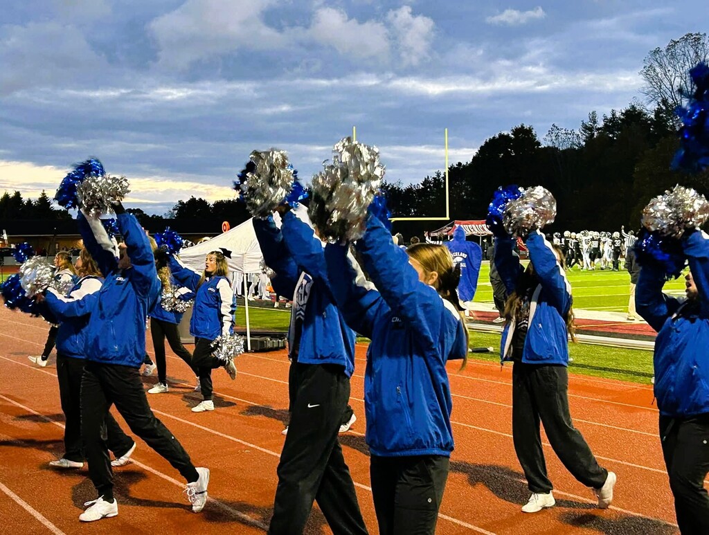 Cheerleaders with pom pons doing a cheer on the sideline