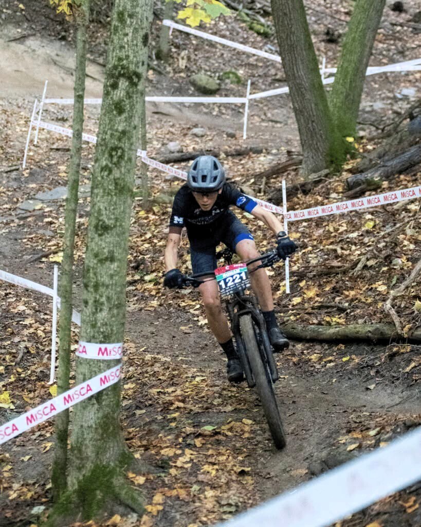 Photo of a kid riding a bike down a dirt path in the woods