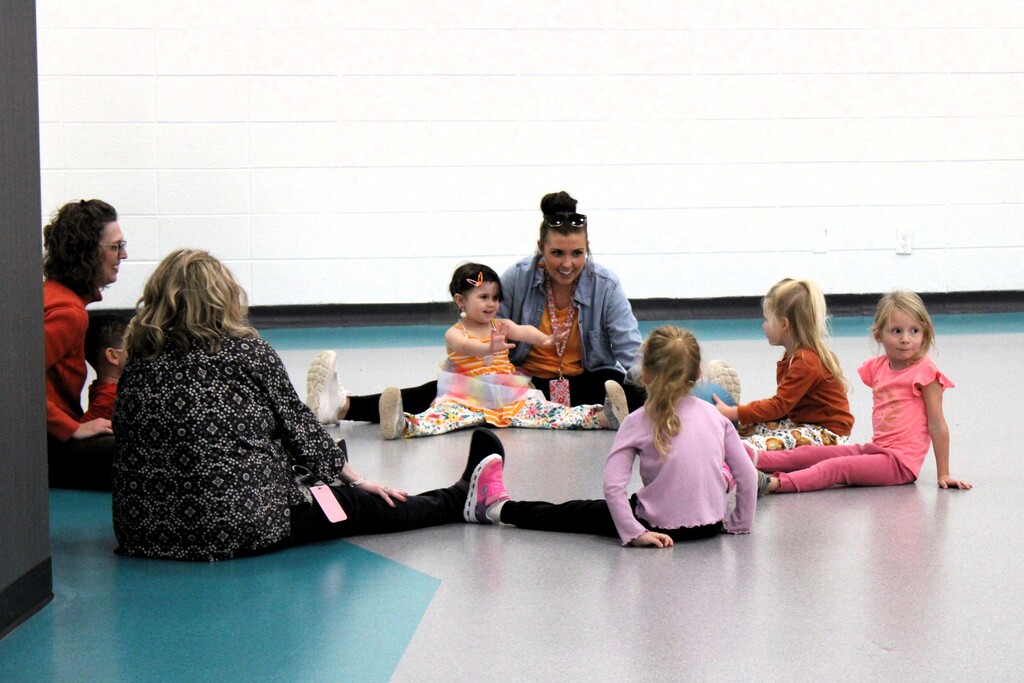 Three women sitting on the floor with kids in a circle