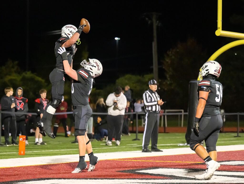 Football player being lifted in the air by teammate in the end zone