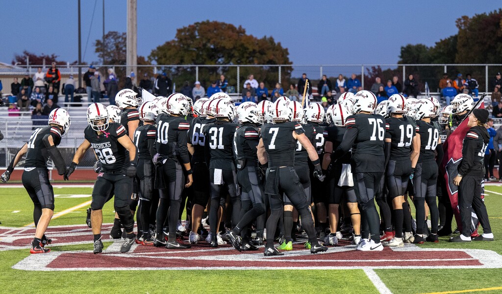 Foootball team huddles up at midfield before a football game