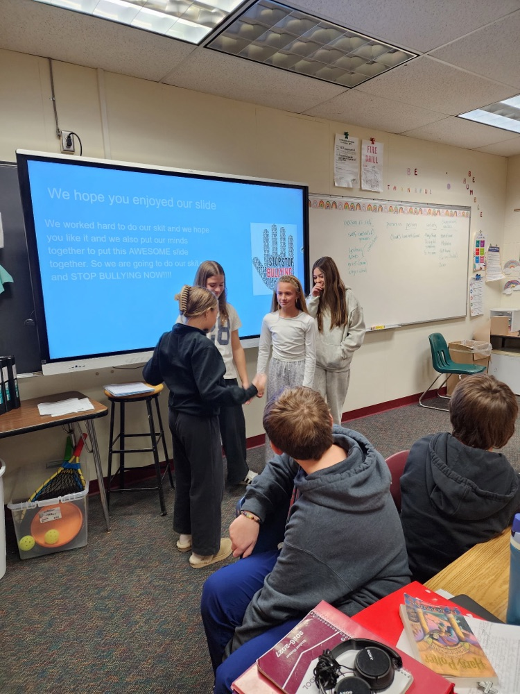 a group of students present in front of a digital whiteboard 