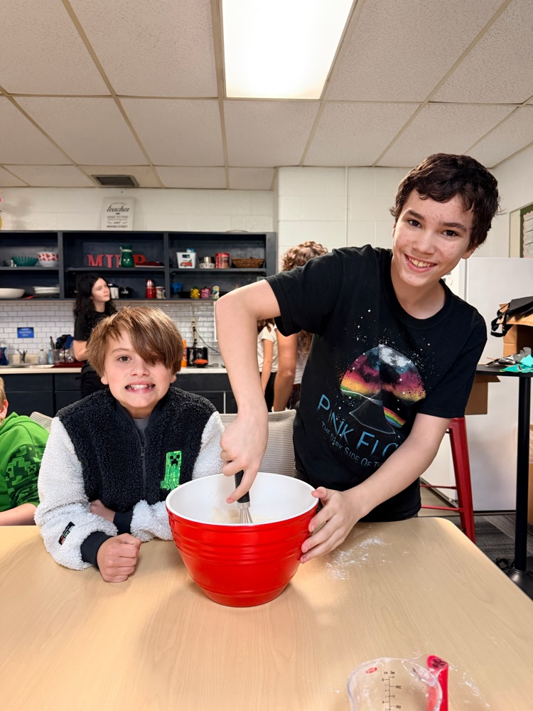 two students mix a red bowl