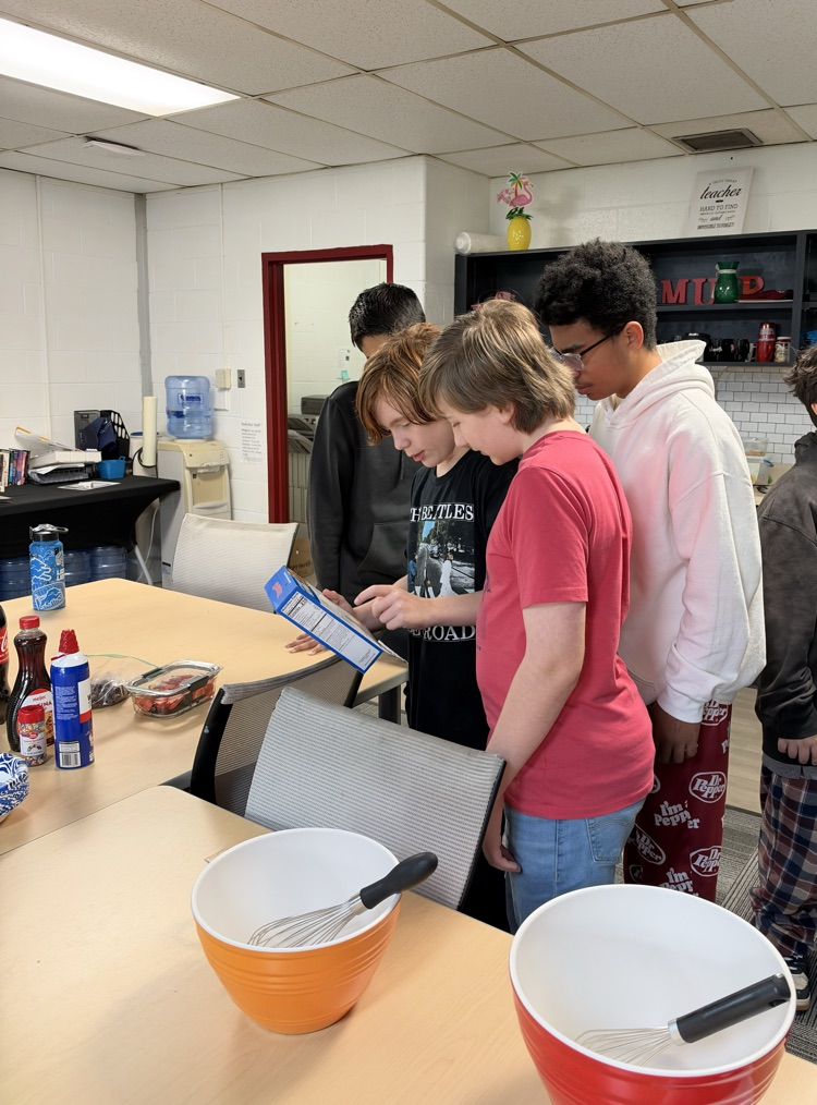 students stand watching while another student mixes