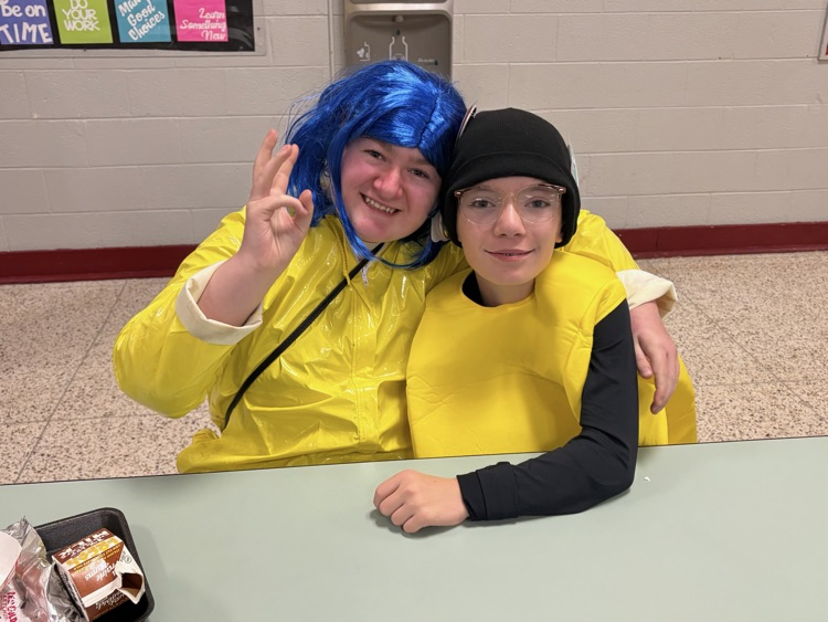 students sit smiling in their yellow costumes 