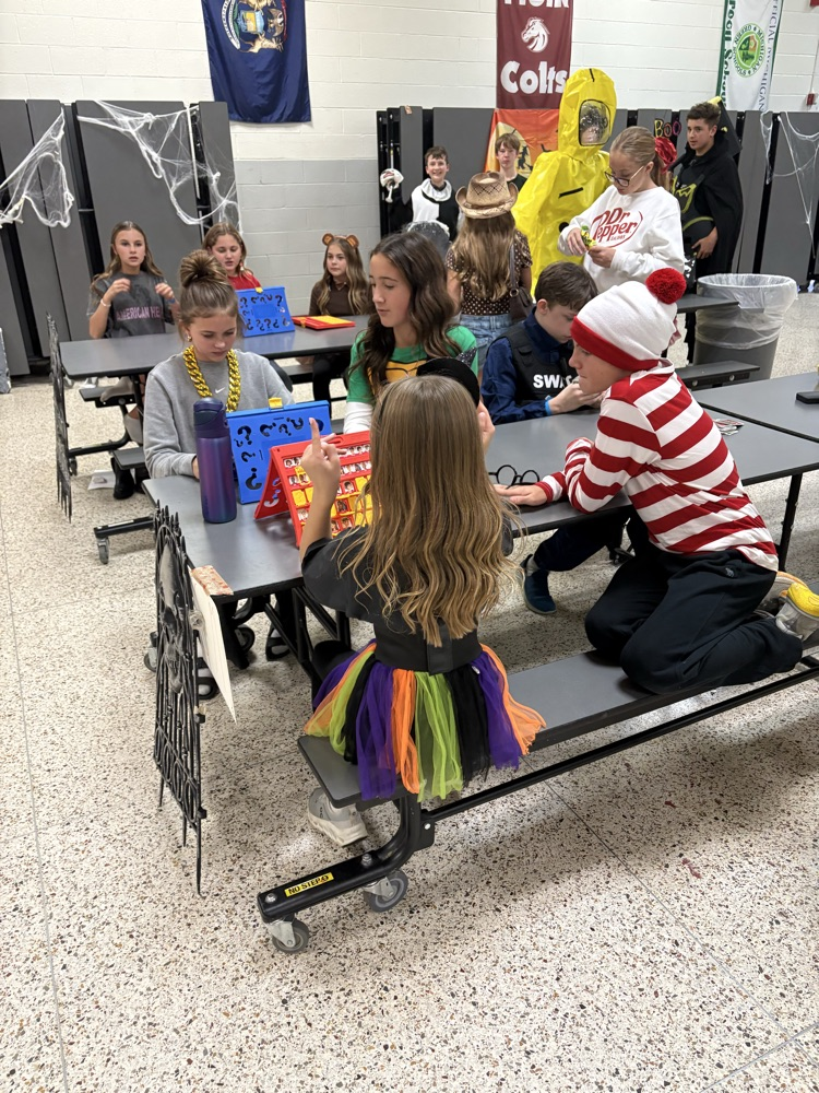 students sit together laughing at a table while dressed for Halloween 