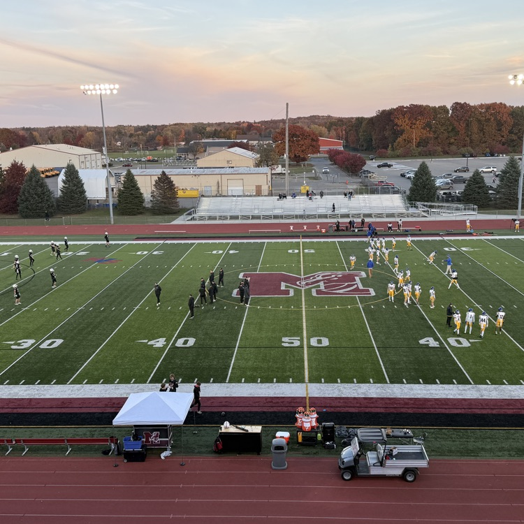 wide photo of football field with two teams warming up 