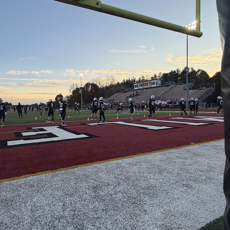 wide shot from under goalpost with football players running