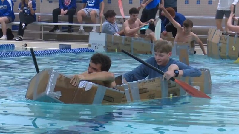 Students in cardboard boats in pool racing 