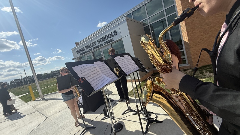 student playing saxophone outside ribbon cutting ceremony
