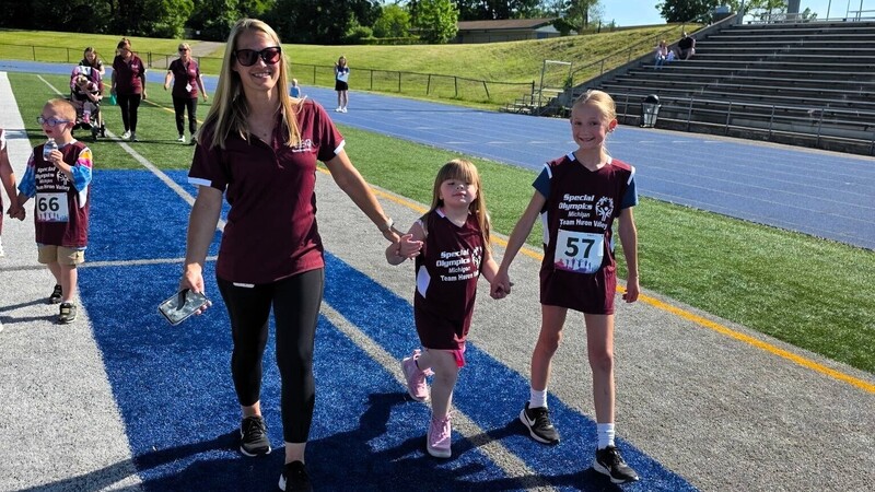 adult holding hands with athlete during unified event