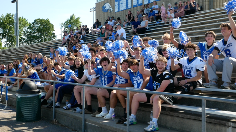 Photo of football cheering on athletes from the bleachers