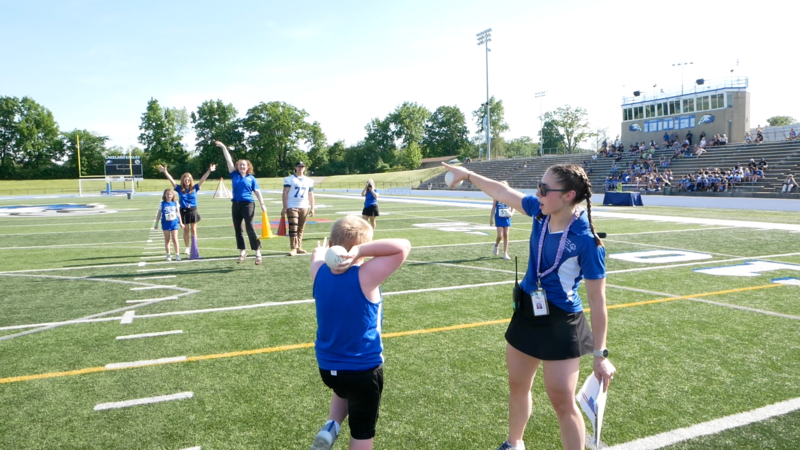 Adults instructing unified athletes on the field before a race