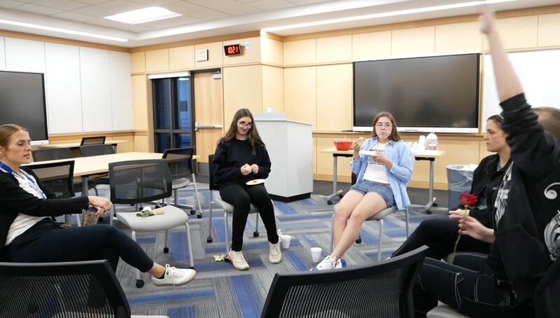 5 students talking while sitted in a circle inside a classroom