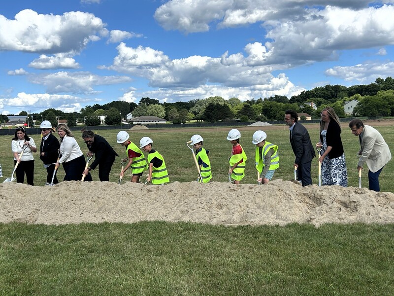 Several people, adults & children, shovel dirt