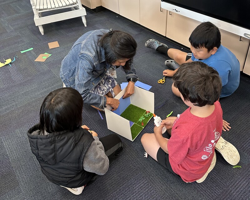 teacher & students on floor working on craft project