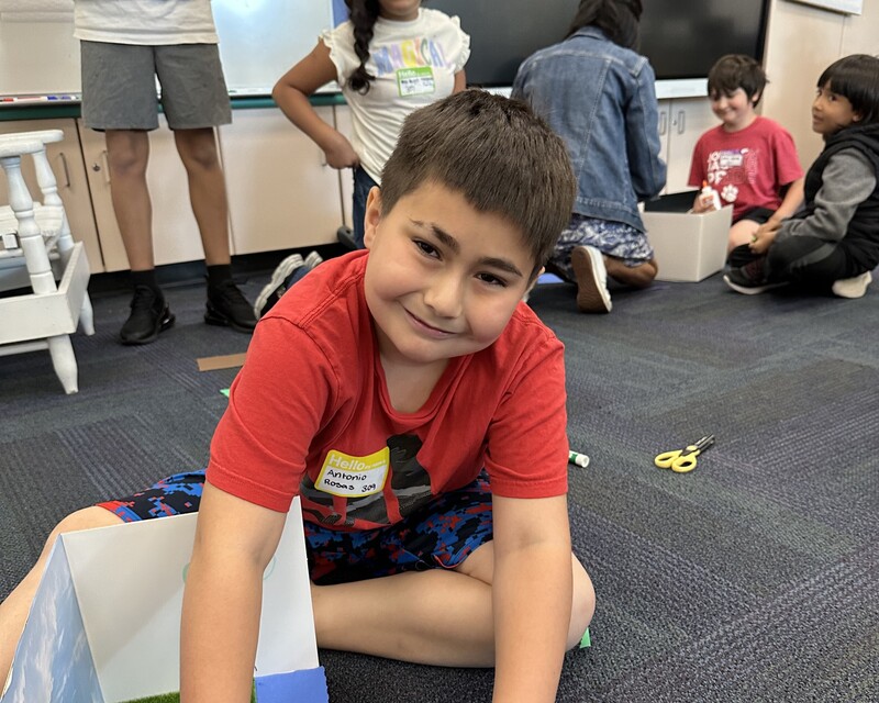 student sitting on floor smiling for a photo