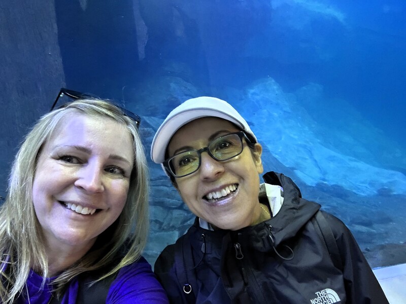 Adults  smiling for a photo in front of a large aquarium 