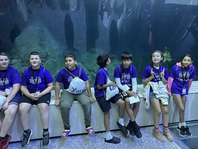 Students posing for photo in front of large aquarium 
