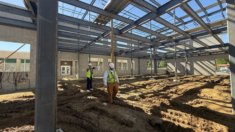 Photo of construction site with cinder block walls up and two men in a hard hats walking