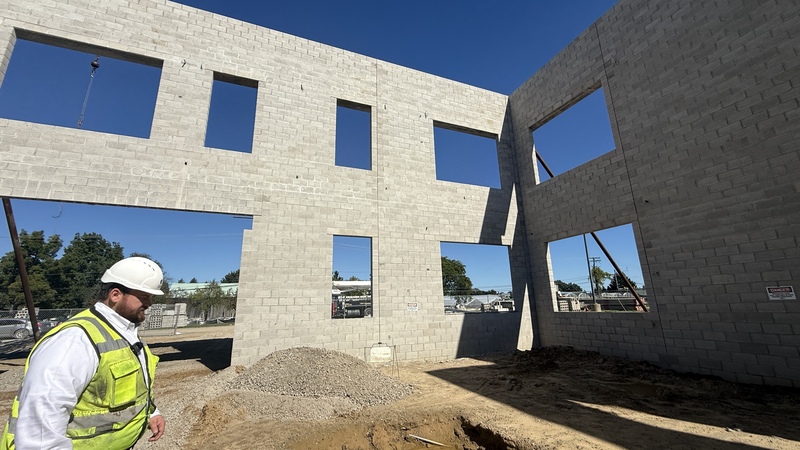 Photo of construction site with cinder block walls up and a man in a hard hat
