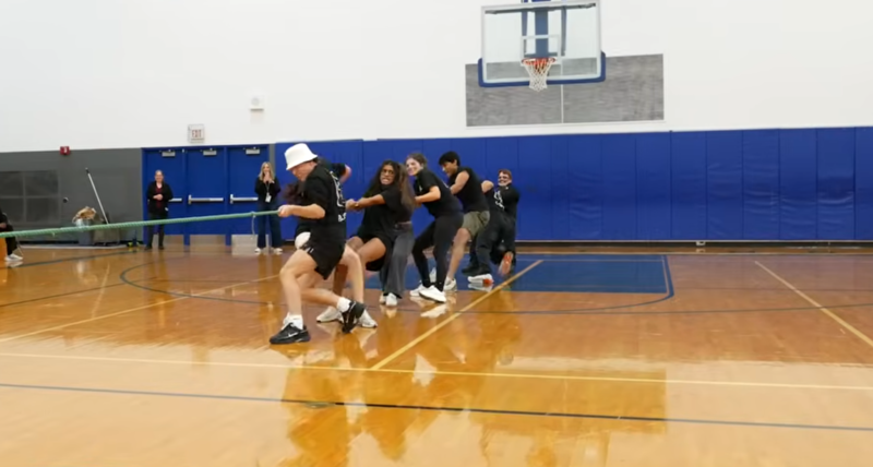Photo of students in black shirts pulling on a rope in a gym