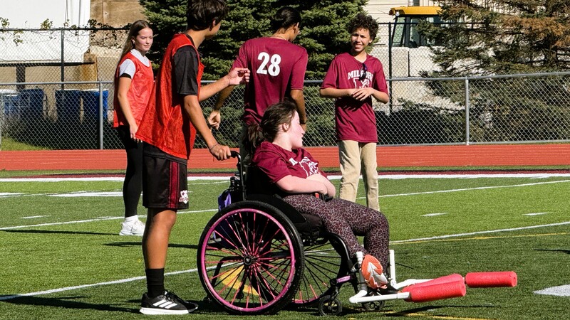 Photo of girl in a wheelchair playing soccer on a field with other players around her
