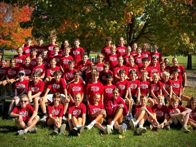 Photo of cross country runners smiling and posing for a picture on a field