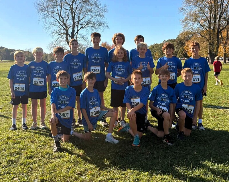 Photo of cross country runners smiling and posing for a picture on a field