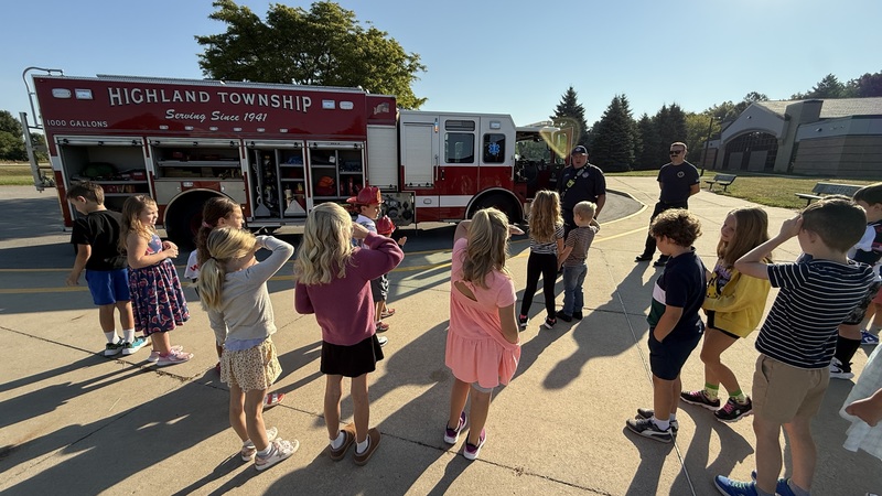 Students learning about FireTrucks and what Firefighters do .