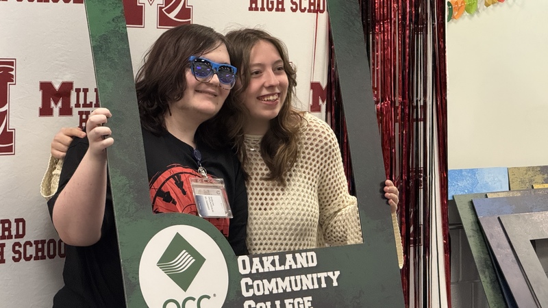 Student posing with OCC sign