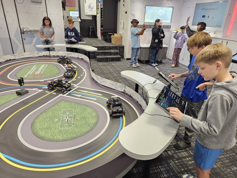 students using technology to control and program cars on small track