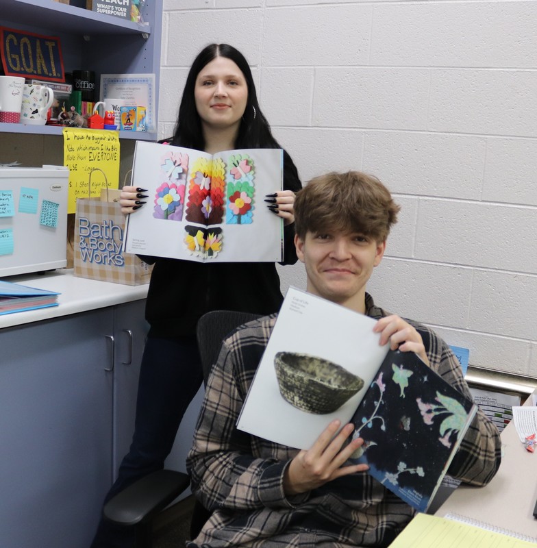 photo of two students holding up artwork.
