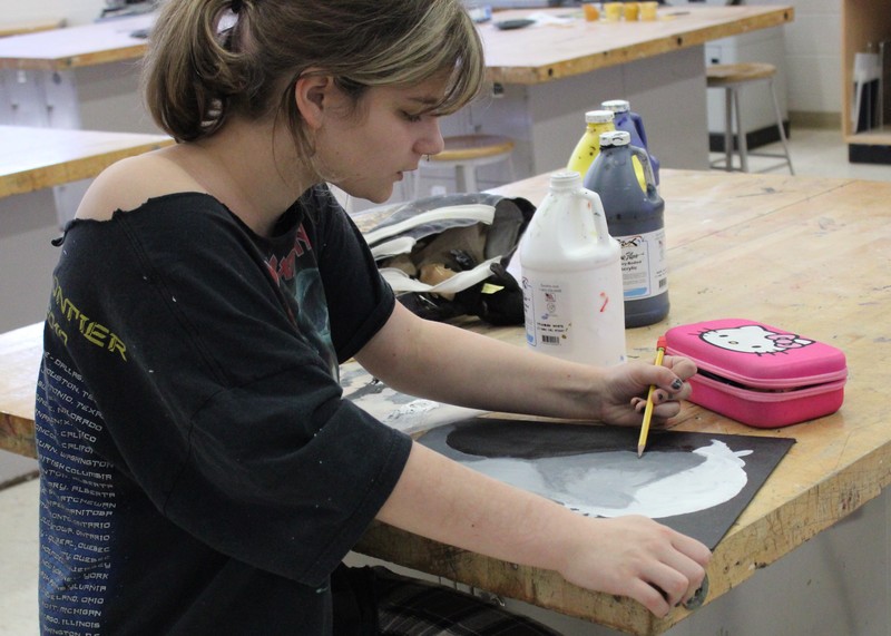 photo of student drawing while seated at a table