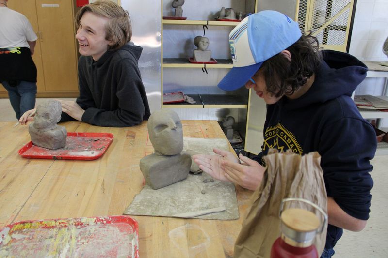two students sitting at a table sculpting
