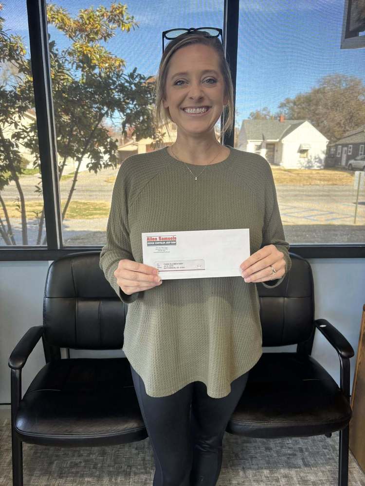 Faris Principal, Jaime Tilton, holds a $300 check from Allen Samuels Chrysler Jeep Ran of Hutchinson