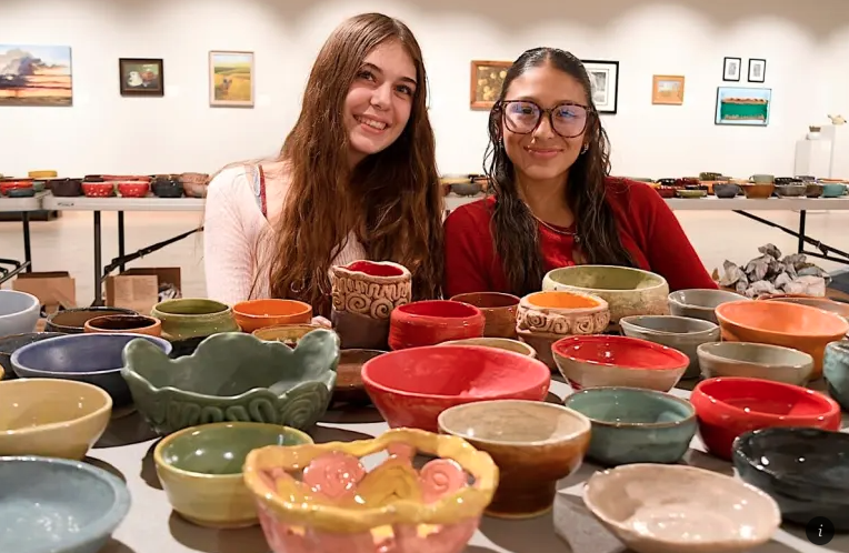 Two female students pose in front of hand-made ceramin bowls
